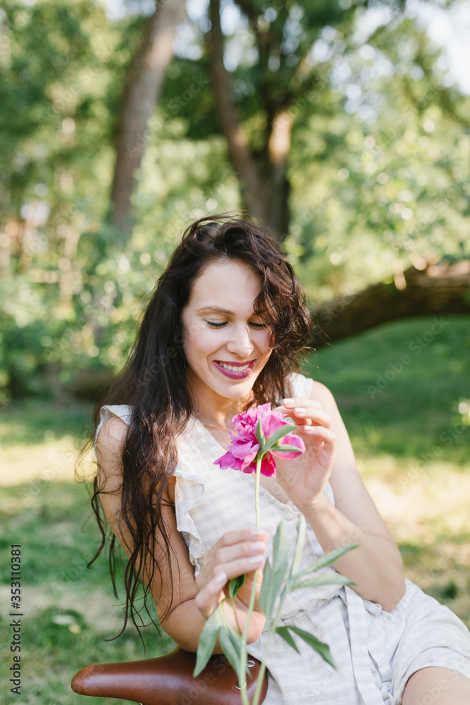 Beautiful girl on a bicycle. Girl sitting on a bicycle with flowers. Bicycle and flowers. A bunch of peonies and a girl. Beautiful girl on a bicycle. Girl sitting on a bicycle with flowers. Bicycle and flowers. A bunch of peonies and a girl.