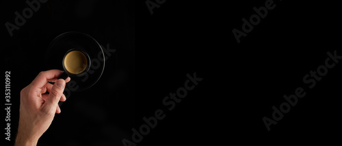 hand holds a black cup with coffee on a black background banner