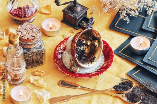 Vintage teacup laying on it's side on a wiccan witch altar for reading tea leaves as a method of divination to foretell the future. Bright yellow cloth in photo with nature elements and tarot cards photo