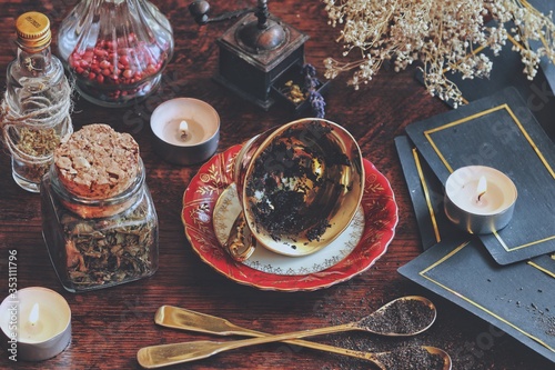 Vintage teacup laying on it's side on a wiccan witch altar for reading tea leaves as a method of divination to foretell the future. Dark moody photo with nature elements and tarot cards in background
