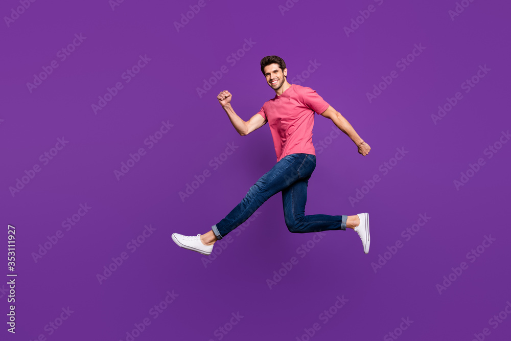 Full length profile photo of attractive guy jump high up run speed shopping center sale prices wear casual pink t-shirt jeans footwear isolated purple color background