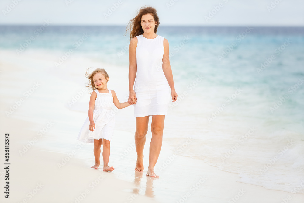 Mother and little daughter walking on beach on Maldives at summer vacation Mother and little daughter walking on beach on Maldives at summer vacation