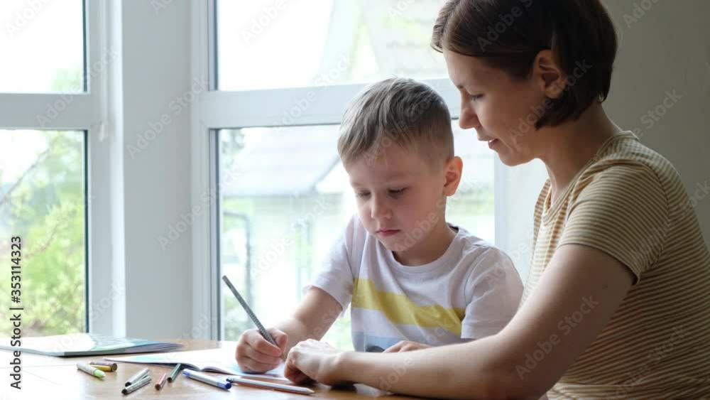 Mother helping his little son child to do school homework, indoors at home Mother helping his little son child to do school homework, indoors at home