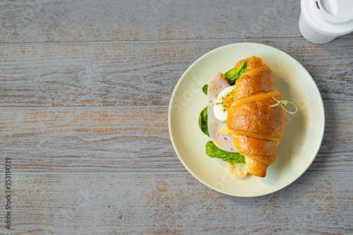 ham sandwich with salad, cheese, egg and mustard sauce and coffee to go cup on light wooden background. space for text, top view
