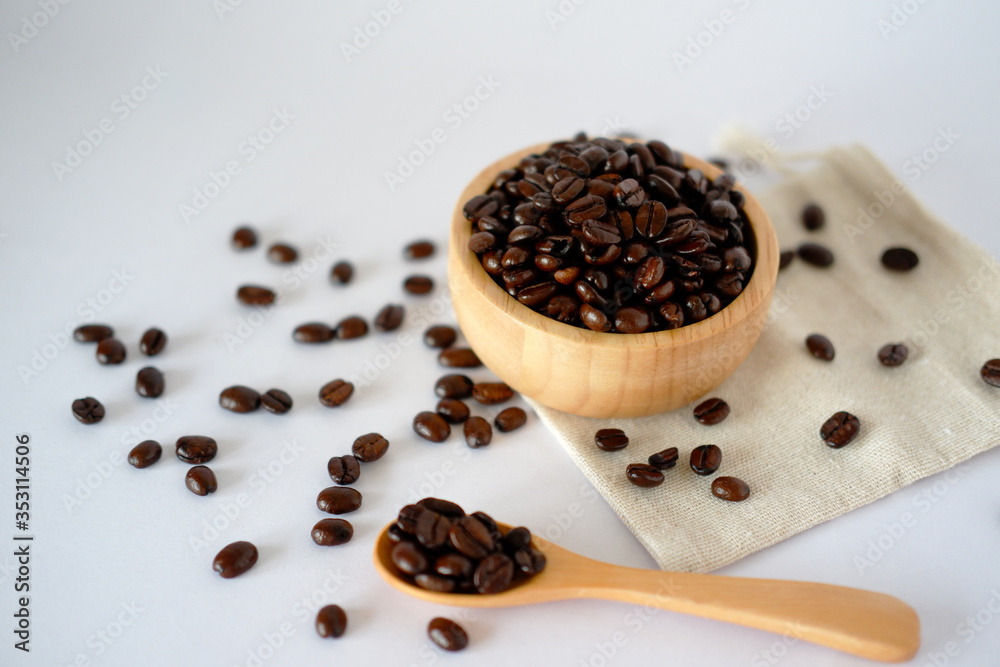 Wooden cup with roasted coffee beans on a white surface The top view with space designed for you. Wooden cup with roasted coffee beans on a white surface The top view with space designed for you.
