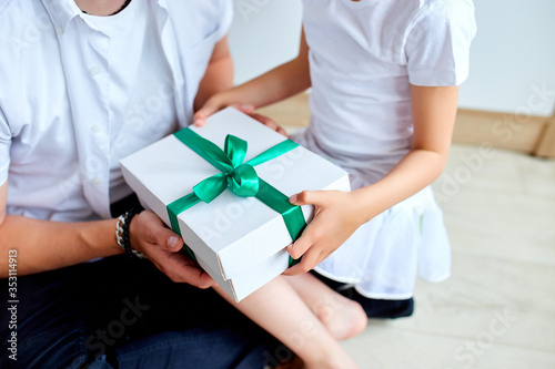 Unrecognizable daughter congratulating dad and giving present on birthday at home. © bondarillia