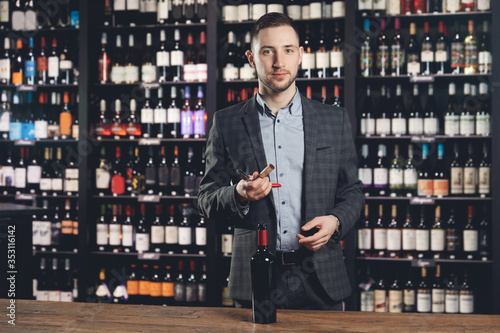 Sommelier man smells wine stopper on corkscrew, assessing taste of drink restaurant