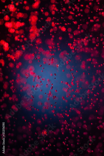 Red drops falling on a blue background. Abstract background with blur at the edges..