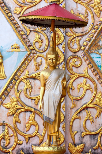 Obraz na płótnie Vertical image Statue of gold  Buddha leela standing with Stucco Laos style on t