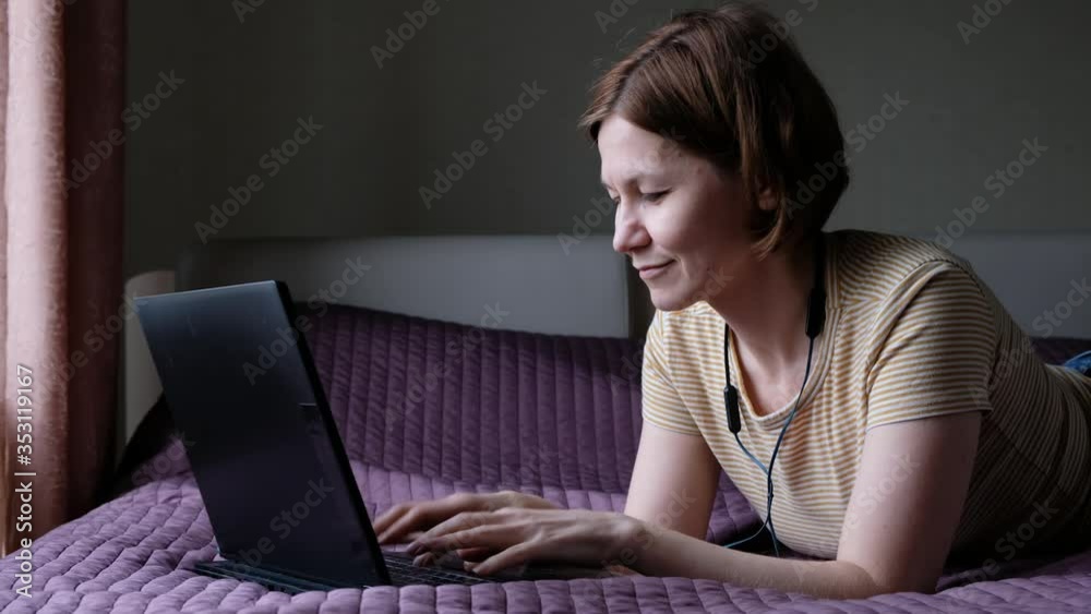 Portrait of woman lying on a bed with laptop, browsing surfing internet Portrait of woman lying on a bed with laptop, browsing surfing internet