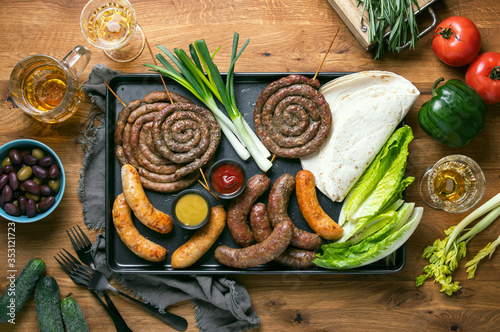 Sausages served with tomato sauce, mustard and beer for pub an outdoor party, top down view