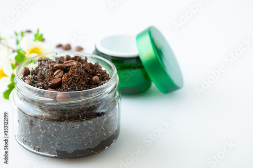 Body scrub made from coffee and sugar in a glass jar and face cream on a white background. The concept of home spa care and beauty.Close-up.