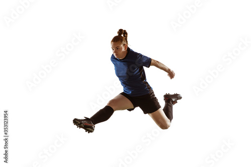 Young female soccer or football player with long hair kicking ball for the goal in flight, jumping high on white studio background. Concept of healthy lifestyle, professional sport, motion, movement. © master1305