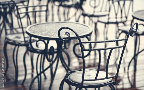 Forged furniture on summer terrace of street cafe after rain. Empty summer terrace without people in the evening  crisis of cafes and restaurants  lack of visitors