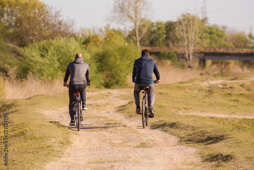 Two men ride bicycles on a country road in nature