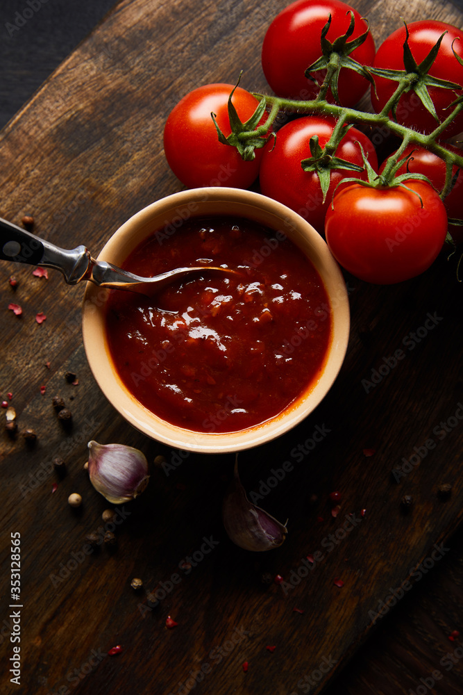 top view of delicious tomato sauce in bowl with spoon near tomatoes and spices on wooden board top view of delicious tomato sauce in bowl with spoon near tomatoes and spices on wooden board