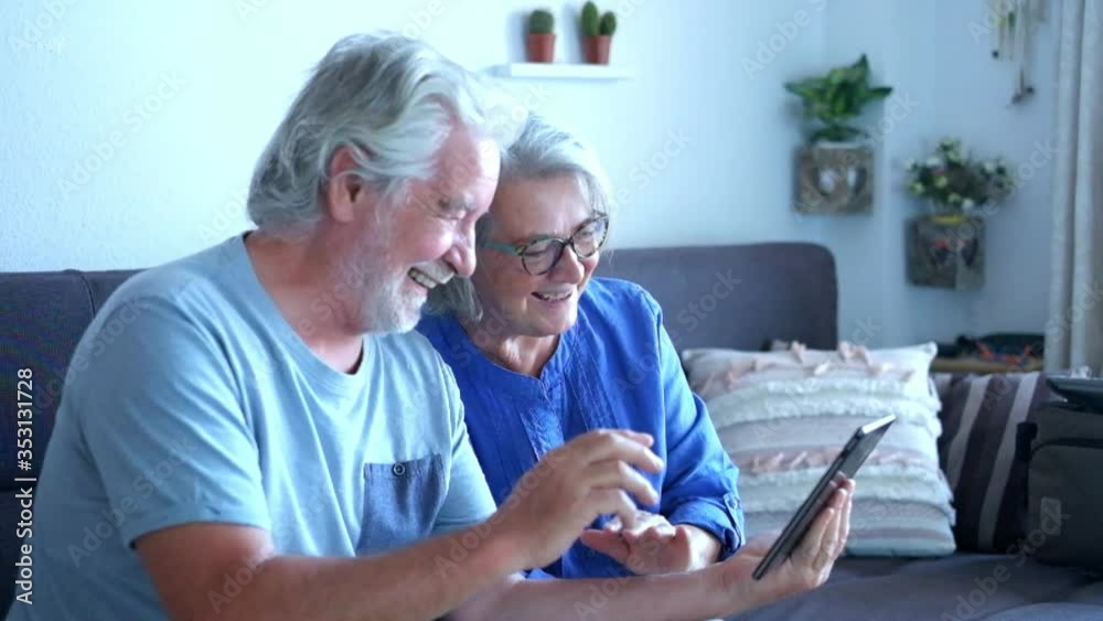 couple of two happy seniors and pensioners at home on the sofa talking with some friends or parents in video call - quarantine lifestyle - couple of two happy seniors and pensioners at home on the sofa talking with some friends or parents in video call - quarantine lifestyle -