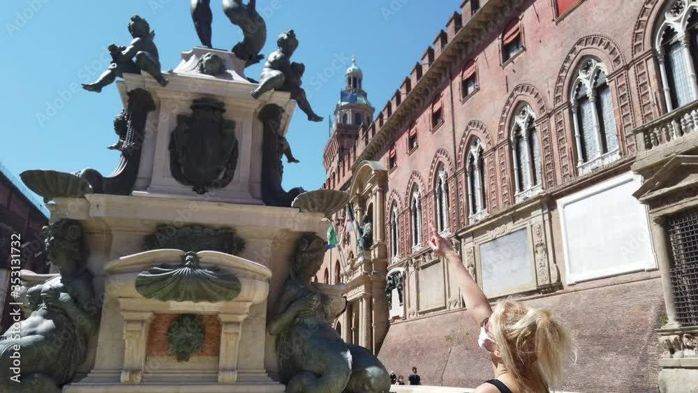 Lifestyle woman with the surgical mask in Maggiore square looking at Neptune statue and San Petronio basilica. Coronavirus after COVID-19 lockdown with social distancing in Bologna city of Italy. Lifestyle woman with the surgical mask in Maggiore square looking at Neptune statue and San Petronio basilica. Coronavirus after COVID-19 lockdown with social distancing in Bologna city of Italy.