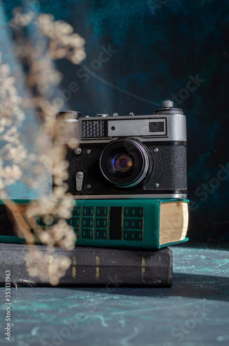 a stack of books and an old camera are on the table