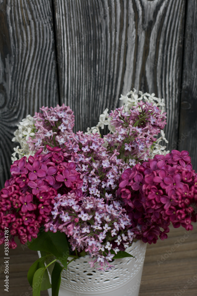 A bouquet of lilacs of different colors. Against the background of painted pine boards.