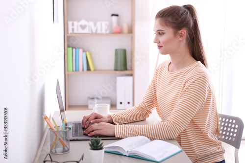The girl works remotely from home using a modern laptop. 