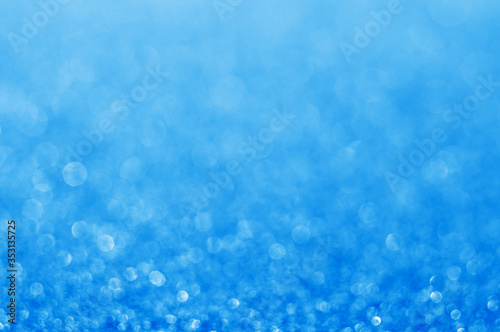Blue defocused glitter background with copy space. Christmas background. Blue holiday glowing abstract background. Blurred bokeh