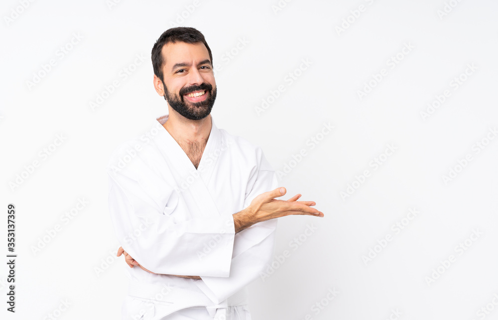 Young man doing karate over isolated white background presenting an idea while looking smiling towards Young man doing karate over isolated white background presenting an idea while looking smiling towards