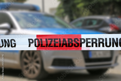 Symbolbild: Polizeiabsperrung mit Polizeiauto im Hintergrund.