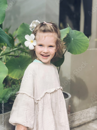 Little Girl with a plumeria flower in her hair against the backdrop of lotus leaves