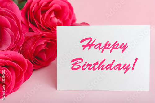 Happy birthday text on card in flower bouquet on pink background. Flower delivery, congratulation card. Greeting card in pink red roses