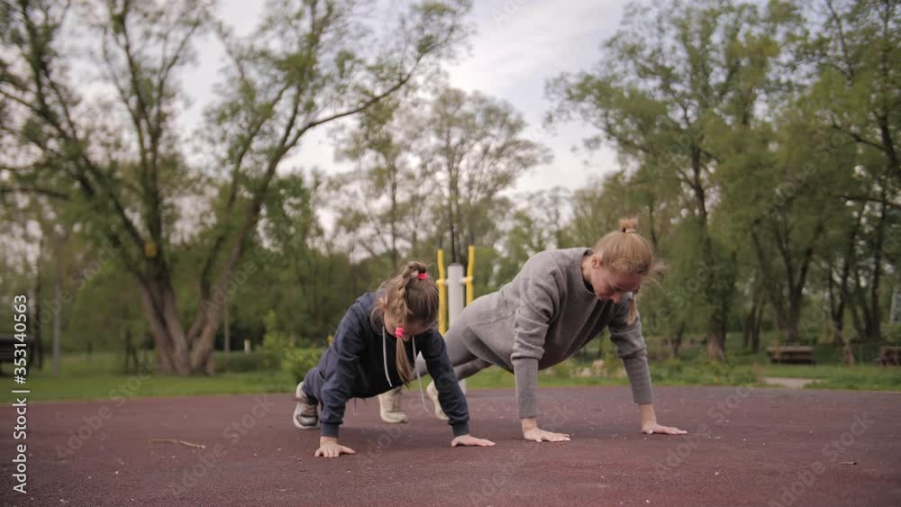 4K Mother and Daughter doing push up exercises on open air sport playground 4K Mother and Daughter doing push up exercises on open air sport playground