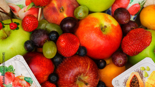 Set of berries and fruits in wooden box. Apple  strawberry  grape  berry and peach on a red brick background.