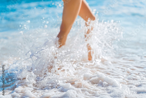 Sea foam at the girl's feet. A girl runs through the waves on a sandy beach. Summer holiday concept.