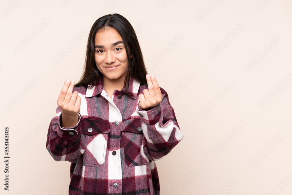 Young Indian woman isolated on beige background making money gesture but is ruined Young Indian woman isolated on beige background making money gesture but is ruined
