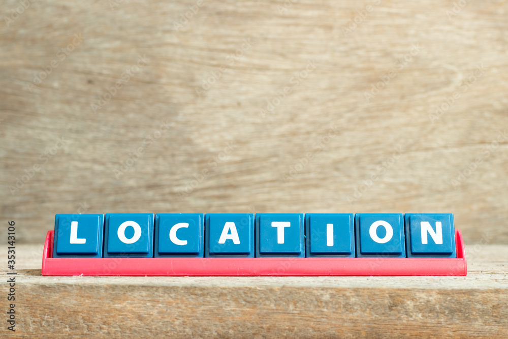 Tile letter on red rack in word lcoation on wood background