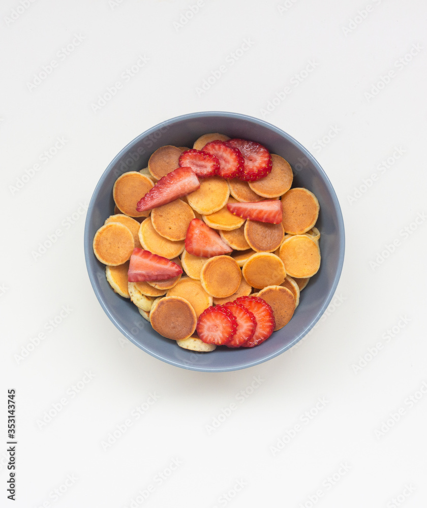 Pancake flakes with sliced strawberries in a gray bowl. Isolate Top view.