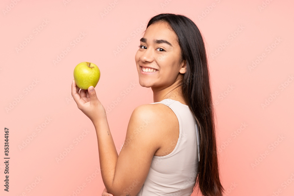Young Indian woman isolated on pink background eating an apple Young Indian woman isolated on pink background eating an apple