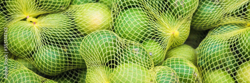 Fresh limes banner in a grid on supermarket shelves. Selective Focus.