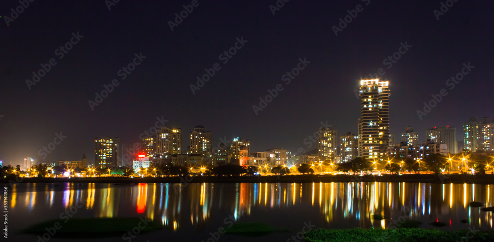 Fototapeta premium night view of the Mumbai city in India looking from Powai lake with reflection of buildings on the water and twinkling city lights