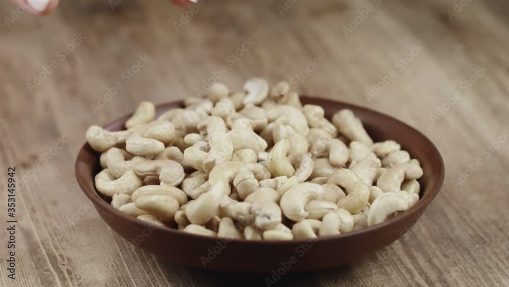 Woman Picks Up A handful Cashew, To Eat, From Her Bowl. took a nut on the right side Woman Picks Up A handful Cashew, To Eat, From Her Bowl. took a nut on the right side