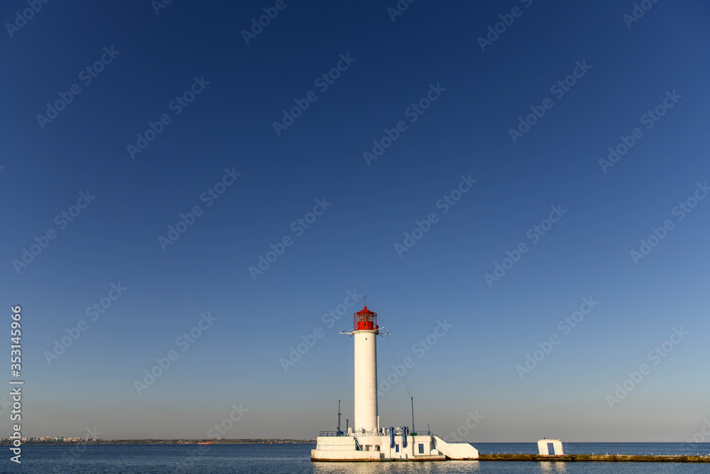 The lighthouse of the port of Odessa illuminated by the setting sun. The lighthouse of the port of Odessa illuminated by the setting sun.