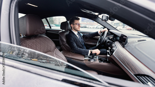 Confident man wearing suit and watch driving car