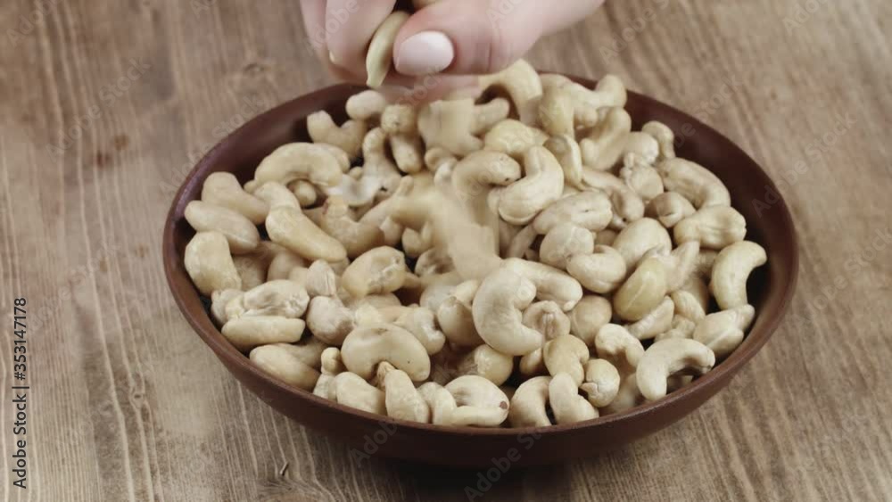 Woman Picks Up A handful Cashew, To Eat, From Her Bowl. took a nut on the left side Woman Picks Up A handful Cashew, To Eat, From Her Bowl. took a nut on the left side