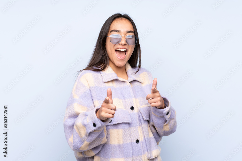 Young Indian woman isolated on blue background pointing to the front and smiling Young Indian woman isolated on blue background pointing to the front and smiling