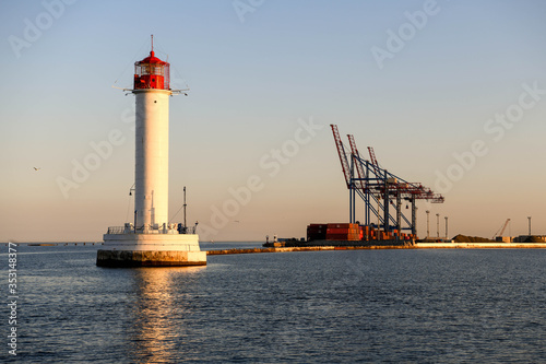 Unloading crane and lighthouse at the port of Odessa at sunset.