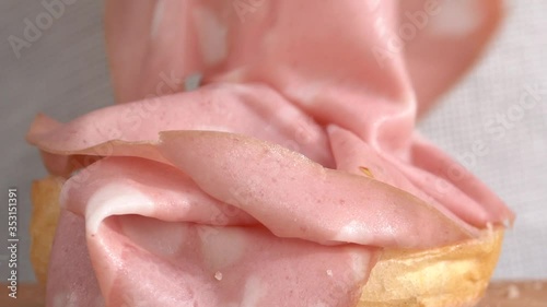 Preparation of a sandwich with mortadella, close-up view, hands working with bread and salami.