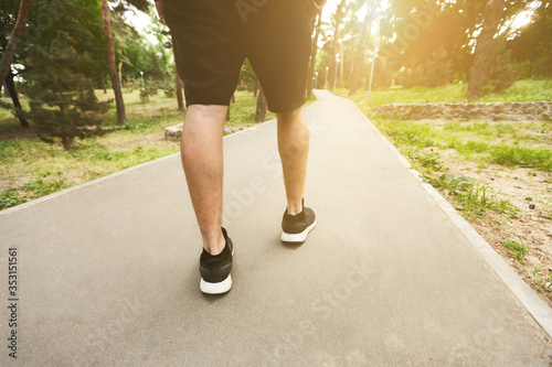 Man running walking in the park, back view of legs