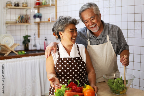 Happiness senior elderly couple having fun in kitchen with healthy food for working from home. COVID-19