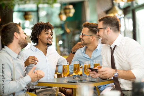 young businessmen in a cafe use a mobile phone and have fun while drinking cold beer