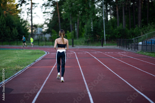 The girl has sport exercises in the stadium. Morning running. A young european woman is jogging on the street. Outfit (look) for doing sports. Healthy lifestyle concept